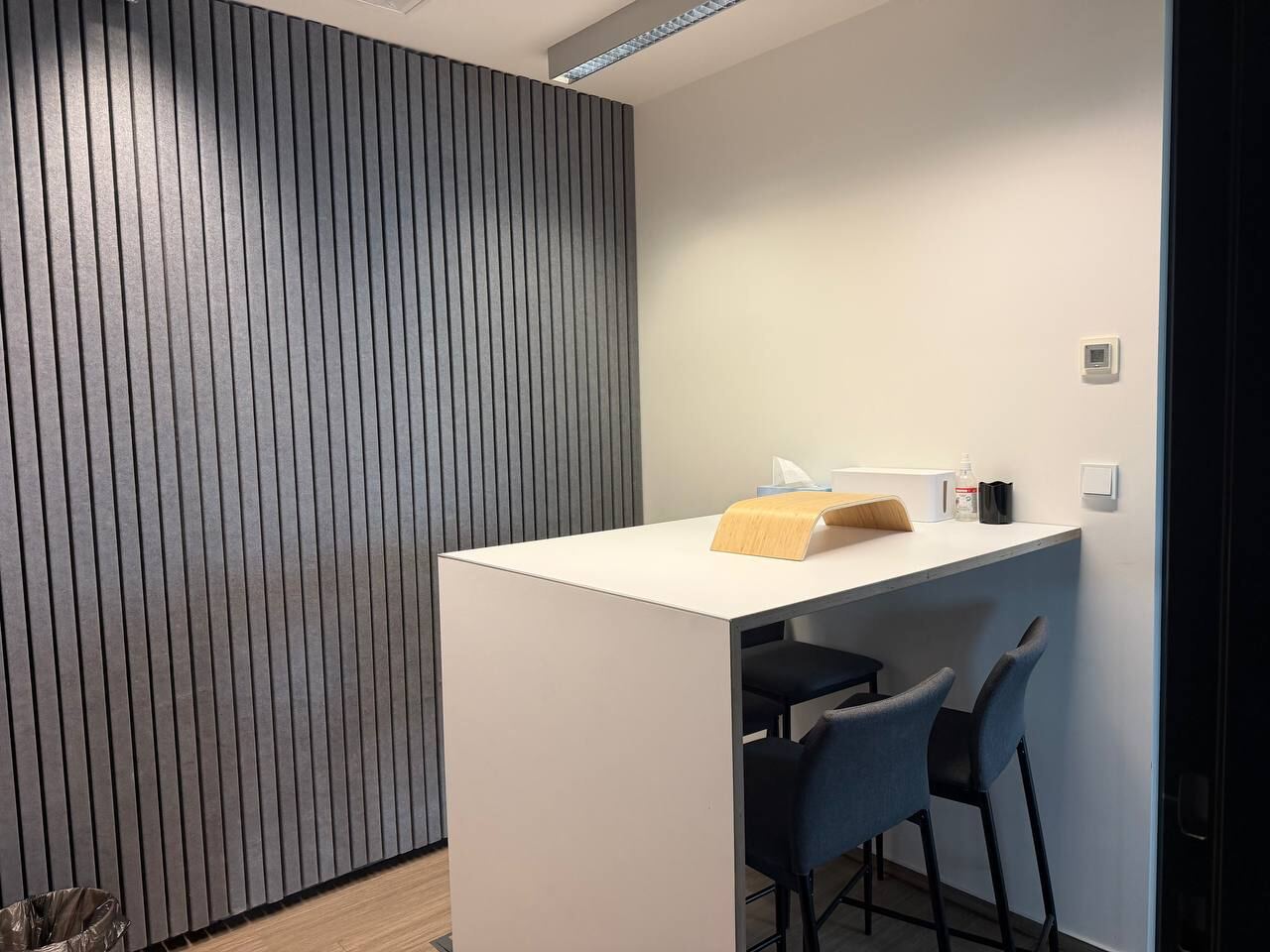 Call room with a high table, two bar stools and a slatted wall